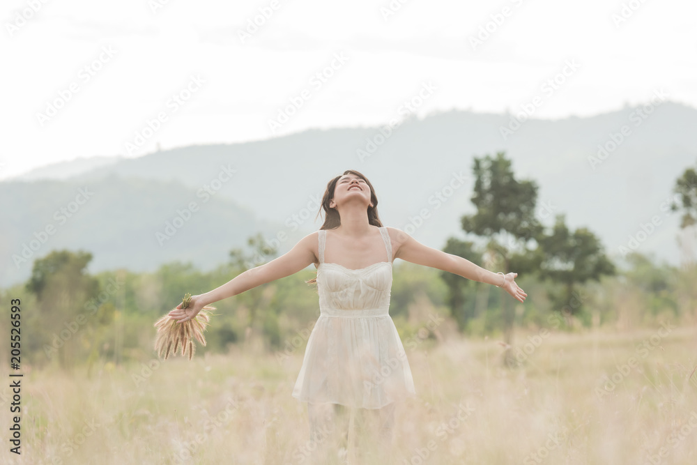 Beautiful woman enjoying meadow field, nice female lying down in meadow of flowers, pretty girl relaxing outdoor, having fun, holding plant, happy young lady and spring green nature, harmony concept