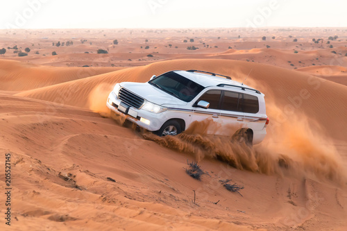 safari on jeeps SUVs in the Arab orange-red sands in the sunset sun. column of sand of wheels, 