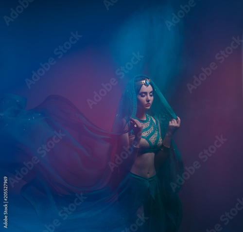 A girl in oriental attire, Queen of the storm. Princess Jasmine. The background is a twist and a strong wind. Studio shooting with mixed light. Artistic Photography