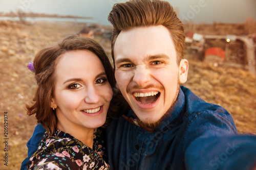 Fotografie Funny couple in love do selfie on hills background.