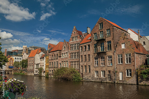Old buildings in front of the canal with blue sky in the City Center of Ghent. In addition to intense cultural life  the city is full of Gothic and Flemish style buildings. Northern Belgium.
