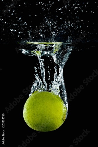 Key lime falling into water with splash
