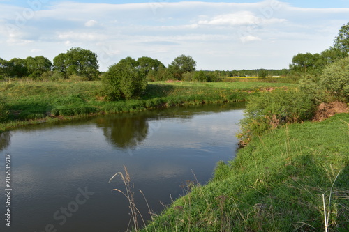 spring landscape, river flowing, green trees, bushes, grass, sky with clouds