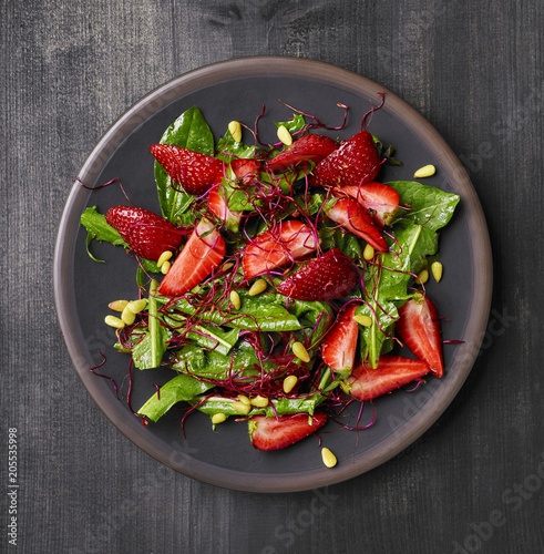 Dandelion salad with strawberries, beetroot sprouts and pine nuts photo