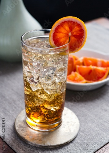 Spritzer in collins glass with ice and bloodorange garnish