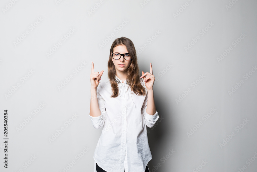 Portrait of a young woman pointing and selecting while happy and smiling on grey background Portrait of a young woman pointing and selecting while happy and smiling on grey background