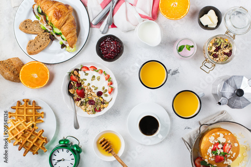 Breakfast table with waffles, granola, yogurt, pancakes, juice, coffee