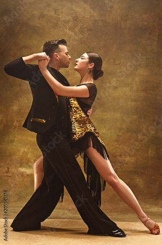 Slika na platnu Dance ballroom couple in gold dress dancing on studio background.