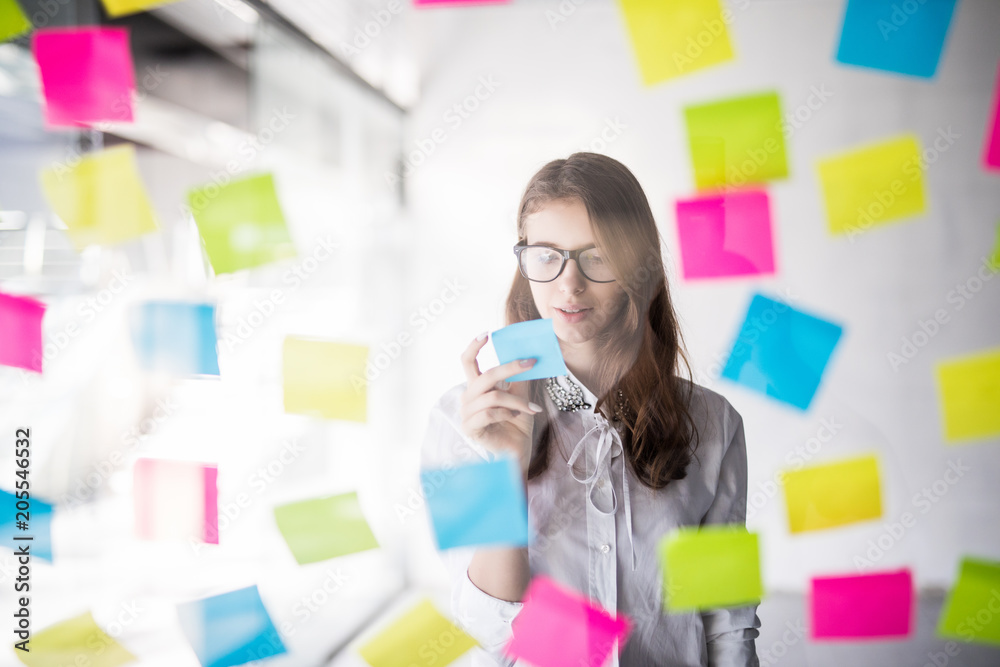 Young beauty business woman read task from stickers glass in office Young beauty business woman read task from stickers glass in office