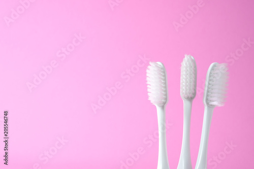 Close-up three white plastic toothbrush on pink background
