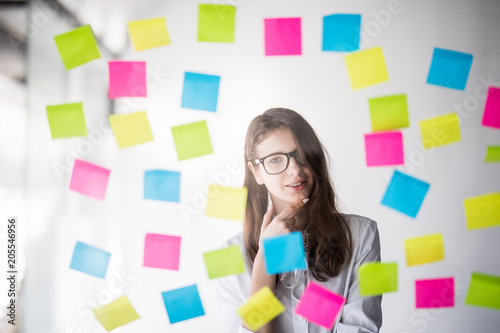 Young business woman making notes on color stickers in office photo