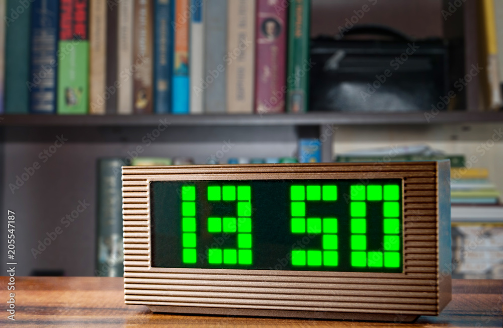 electronic clock on the background of the bookshelf electronic clock on the background of the bookshelf