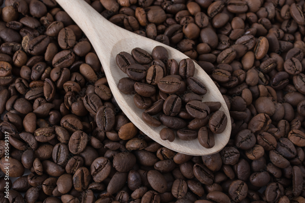 A wooden spoon with coffee beans as background. Close up A wooden spoon with coffee beans as background. Close up