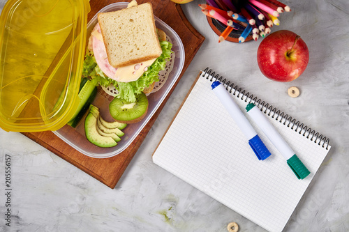 Foto Concept of school lunch break with healthy lunch box and school supplies on whit