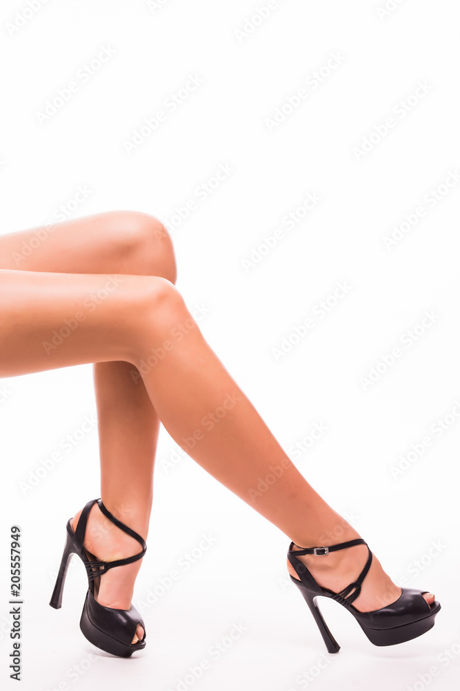 Pretty young female legs with black high heels on white background Pretty young female legs with black high heels on white background