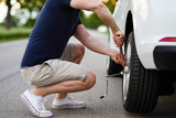 Man changing tire with wheel wrench on broken car