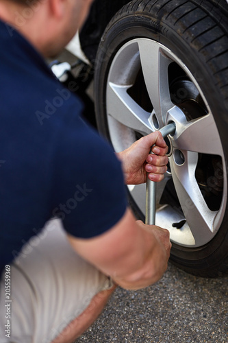 Man changing car tire with wheel wrench, close up
