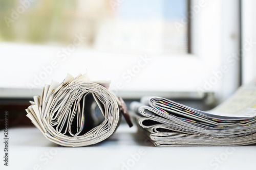 Journals with news. Newspapers folded and rolled and stacked in a pile, side view close up