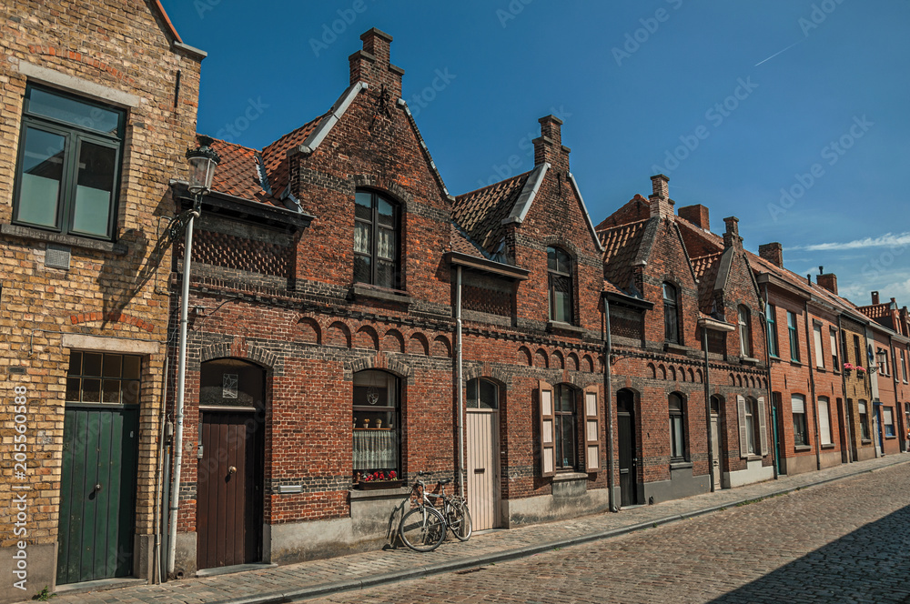 Brick facade of houses in typical Flanders’s style and bicycle, in street of Bruges. With many canals and old buildings, this graceful town is a World Heritage Site of Unesco. Northwestern Belgium.