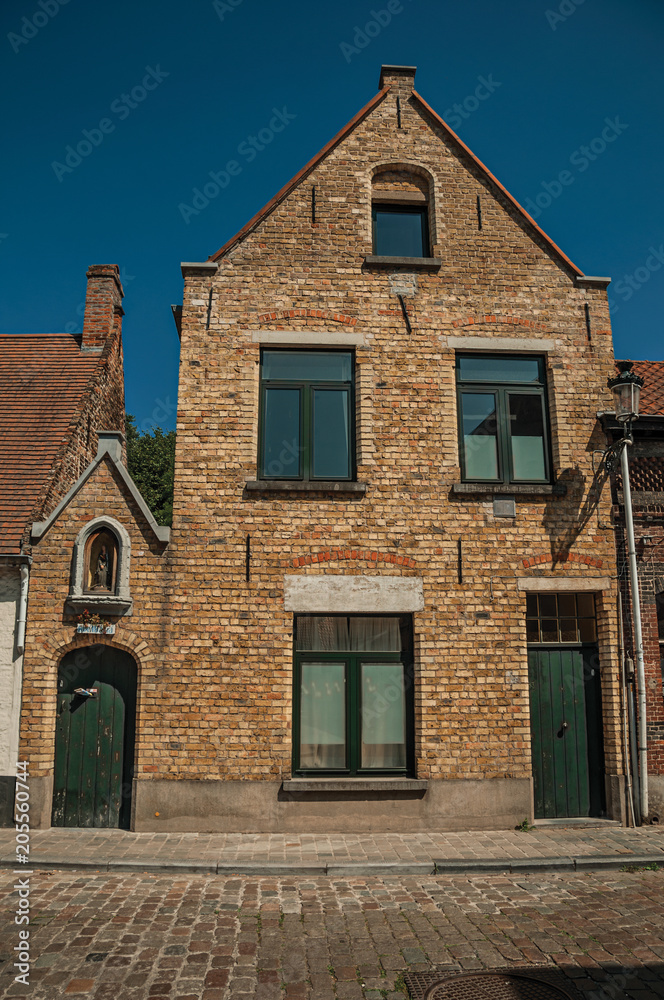 Brick facade of old houses and doors with blue sky, in an empty street of Bruges. With many canals and old buildings, this graceful town is a World Heritage Site of Unesco. Northwestern Belgium.
