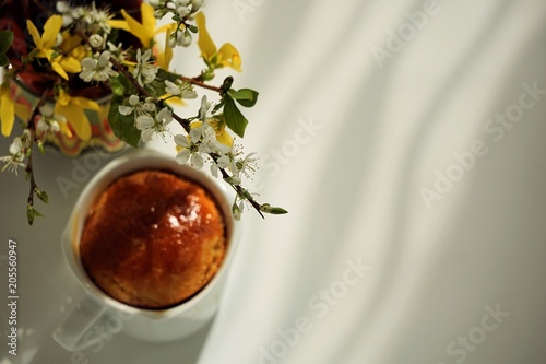 Kitchen still life. morning flowers with freshly baked bun. white background. light from the window. photo