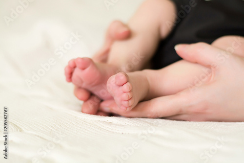 The legs of the newborn in the hands of the mother