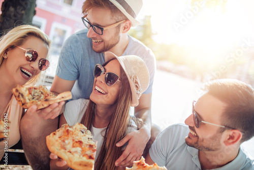 Close up of four young cheerful people eating pizza