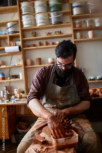 Portrait of a male potter in apron working in his studio, selective focus, close-up photo