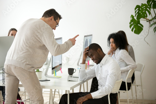 Angry white boss scolding rebuking incompetent black office employee, dissatisfied ceo shouting at african american worker for bad work or failure, reprimand or racial discrimination at work concept