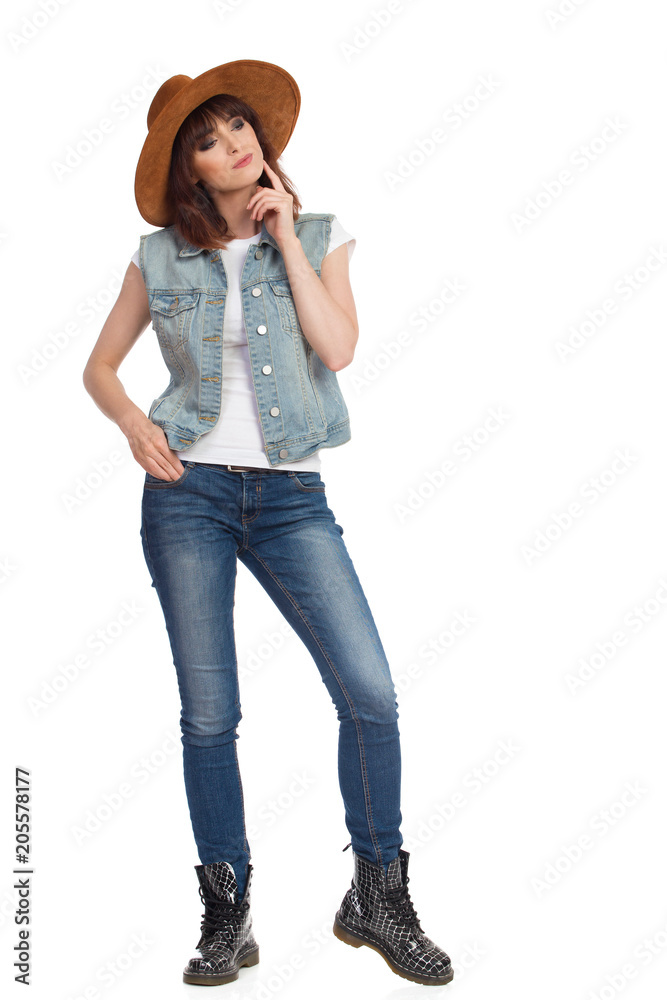 Young Woman In Jeans Vest And Brown Hat Is Standing And Thinking Young Woman In Jeans Vest And Brown Hat Is Standing And Thinking