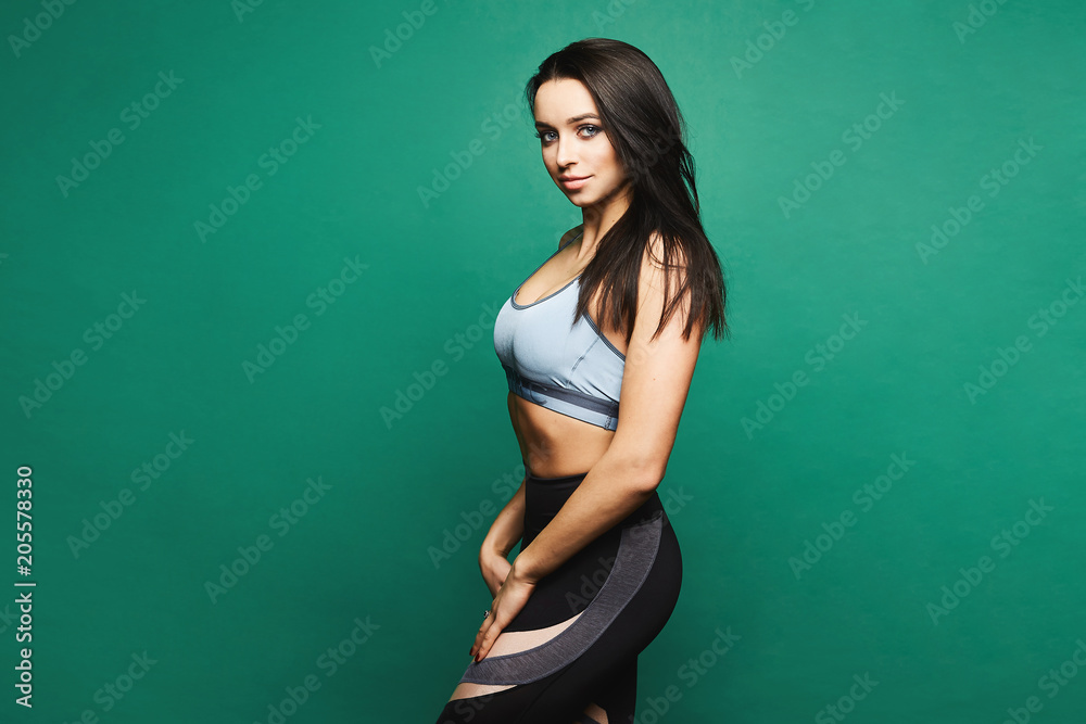 Sporty and sexy brunette model girl with blue eyes and perfect body in sport  tight black leggings and top, posing at green background in studio Stock  Photo | Adobe Stock