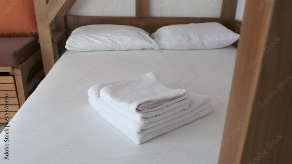 A comfortable bed with white sheets, towels and pillows in a hotel room is waiting for new vacationers A comfortable bed with white sheets, towels and pillows in a hotel room is waiting for new vacationers