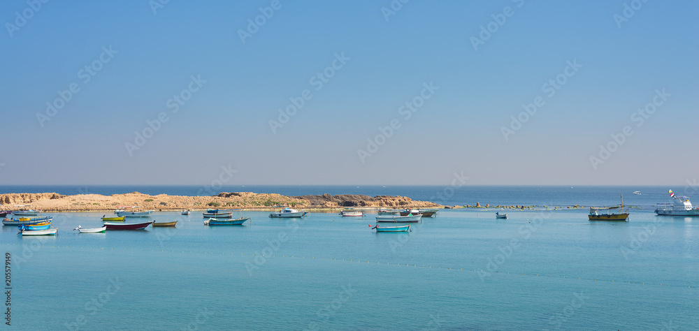 Calm Mediterranean sea with clear sky, small boats and small island at the coast of Alexandria, Egypt