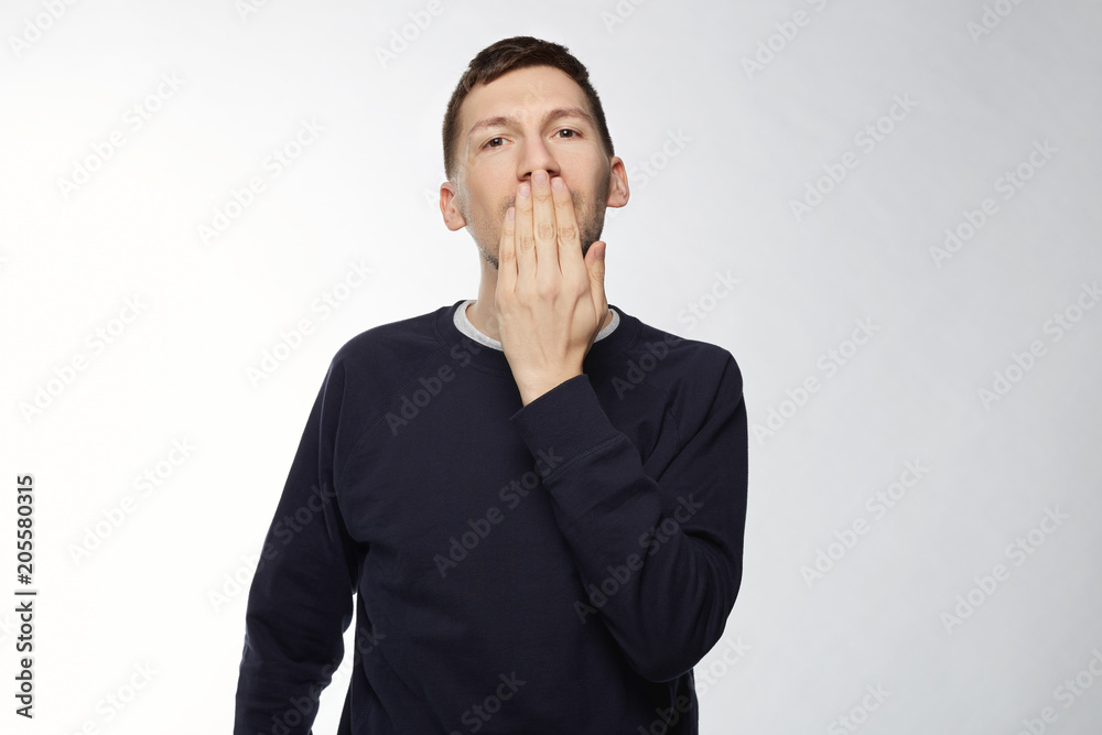 Headshot of handsome European male on white, dressed casually in blue jacket, closing mouth not to scream, keeping secret of important affair, smiling with eyes, feeling advantage of his knowledge. Headshot of handsome European male on white, dressed casually in blue jacket, closing mouth not to scream, keeping secret of important affair, smiling with eyes, feeling advantage of his knowledge.