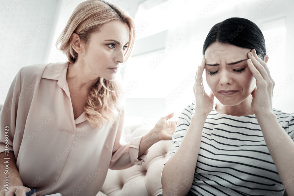 Im with you. Caring pleasant serious woman sitting on the sofa and calming her friend talking to her. Im with you. Caring pleasant serious woman sitting on the sofa and calming her friend talking to her.