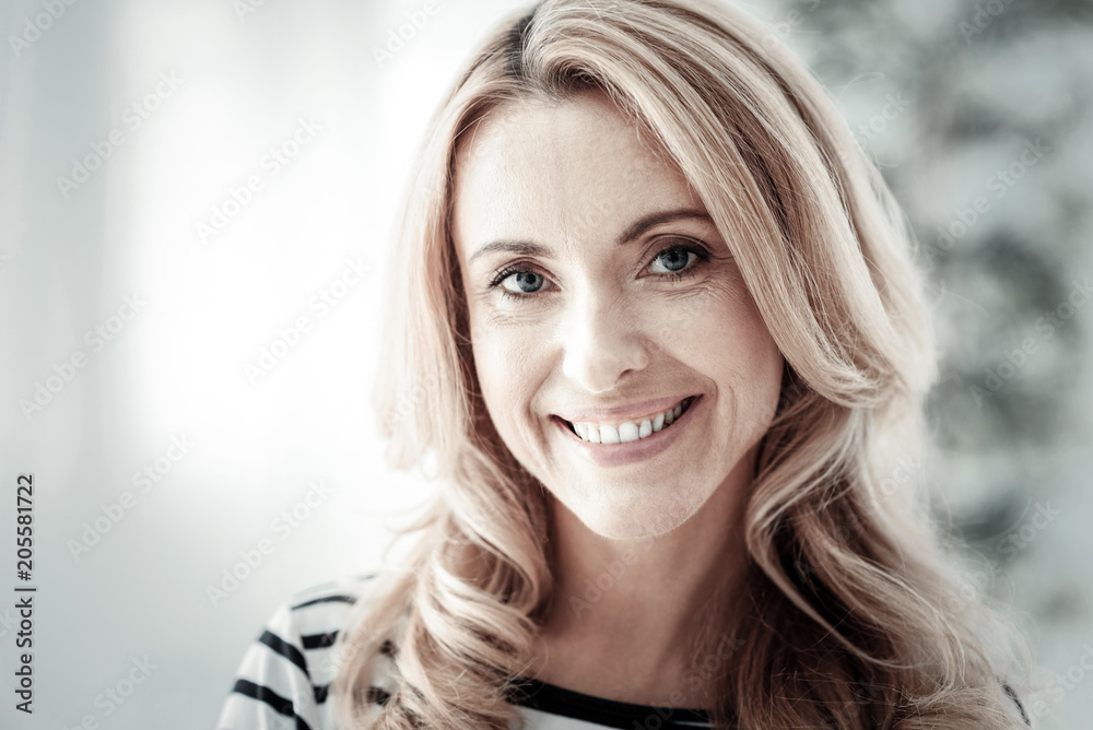 Good mood. Pleasant cute blonde woman being in the bright room standing and smiling. Good mood. Pleasant cute blonde woman being in the bright room standing and smiling.