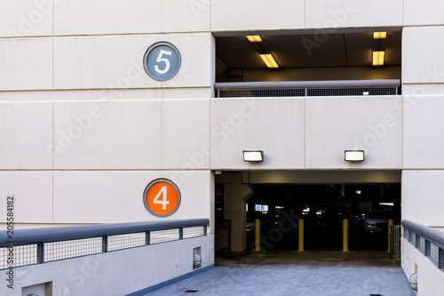 Retail department store mall parking garage with colorful color coded numbers for story level, cars, bridge passage to high building photo