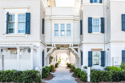 White beach wooden wood architecture, passage path way with green landscaping shrubs, bushes, rocky rock sidewalk, windows, nobody for retirement or vacation apartment condo town