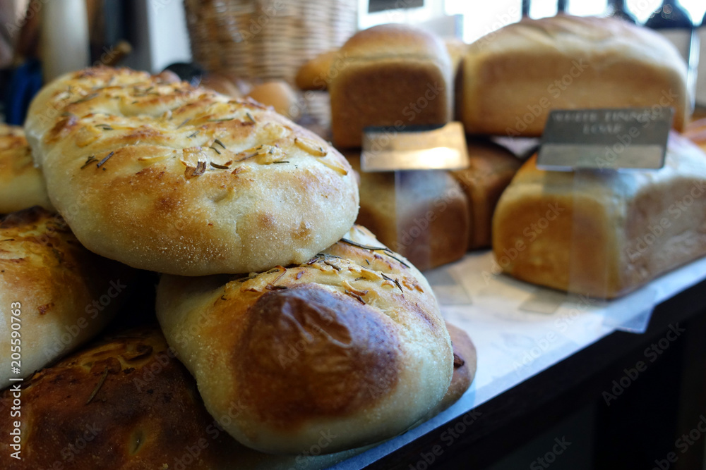 Shallow focus close up of rosemary and garlic focaccia bread, with other loaves in blurred background Shallow focus close up of rosemary and garlic focaccia bread, with other loaves in blurred background
