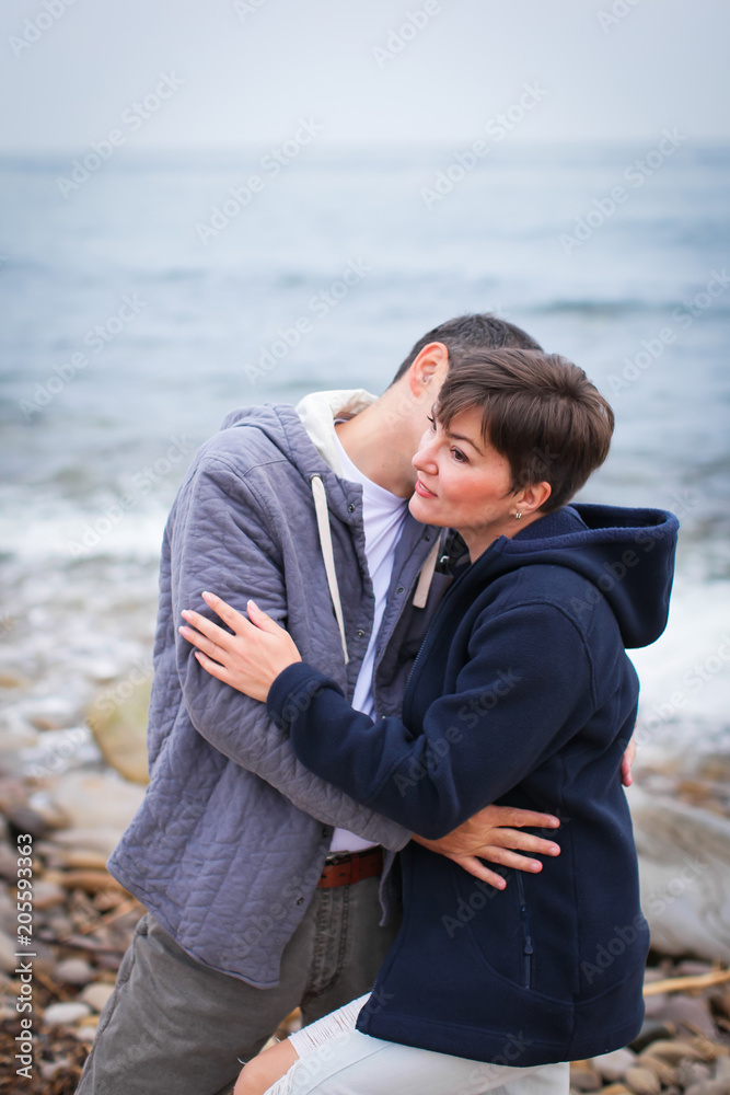 Beautiful couple on the beach at sunset wearing casual clothes