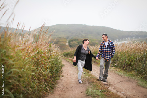 Loving attractive middle-aged couple walking along the road towards the camera