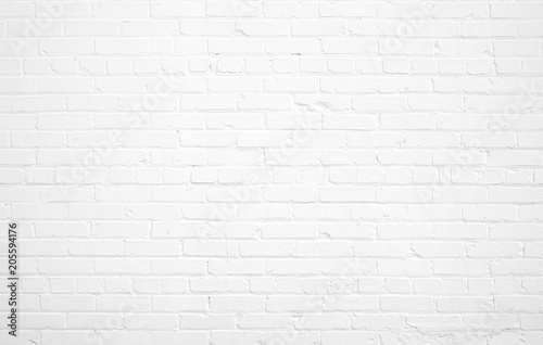 Faded white painted brick wall surface with highlights and shadows. Neutral light gray flat texture and pattern. Architectural masonry work on a building.