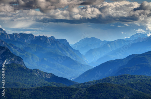 Northern Italian mountain landscape with Piave river valley in glowing blue haze and forested ridges of Alpi Carniche and Dolomiti mountain ranges, Veneto and Friuli Venezia Giulia Italy Europe