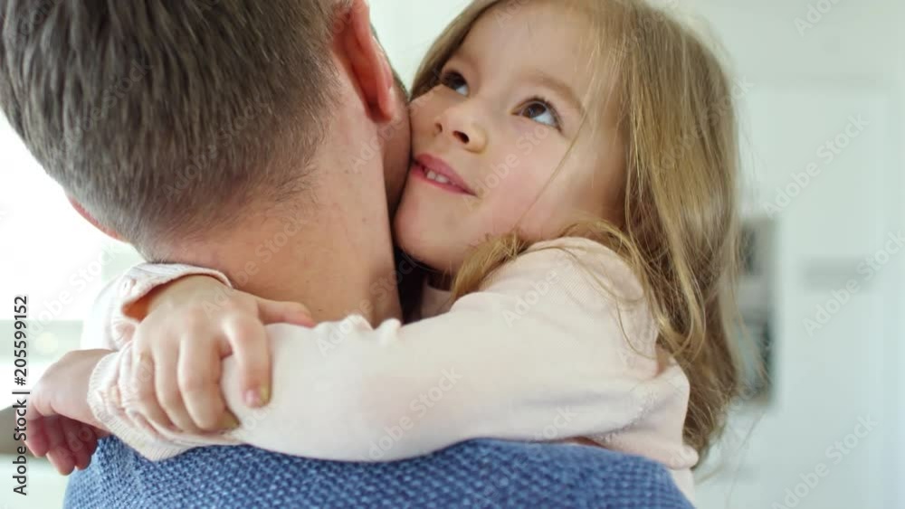 Medium shot of adorable little girl sitting on fathers arms and hugging him with affection Medium shot of adorable little girl sitting on fathers arms and hugging him with affection