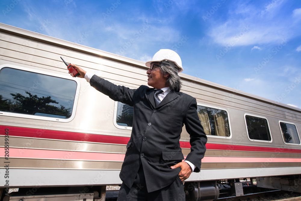 Asian business man pointing with Walky Talky with blurry moving train in background Asian business man pointing with Walky Talky with blurry moving train in background