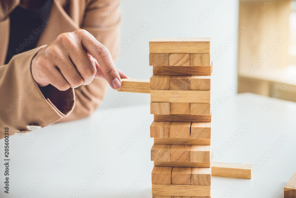 Alternative risk plan and strategy to growth profit in business, Young intelligent business woman playing the wood game, hands of executive placing wood block on the tower Alternative risk plan and strategy to growth profit in business, Young intelligent business woman playing the wood game, hands of executive placing wood block on the tower