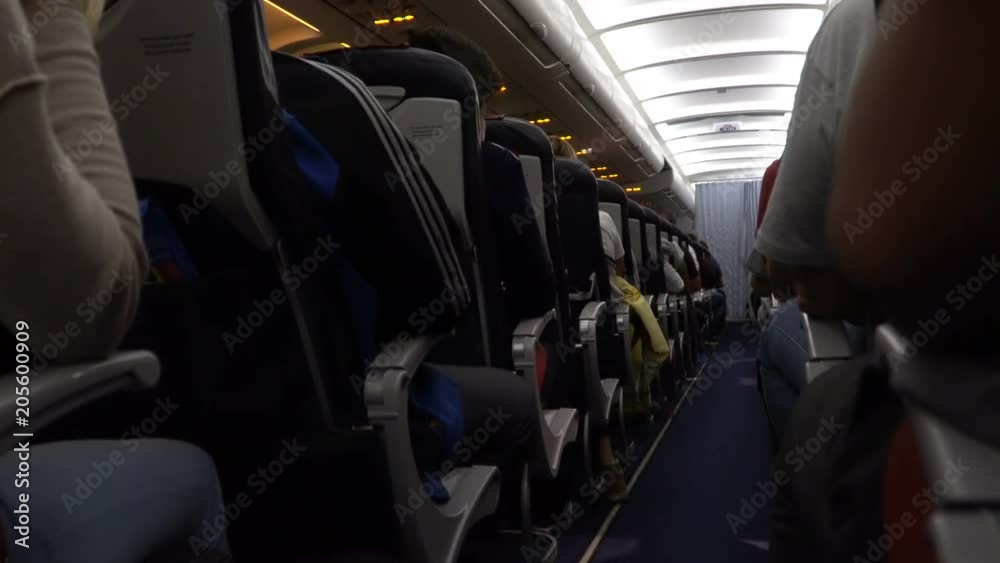 Interior of airplane with passengers on seat during flight. Chairs on aisle Interior of airplane with passengers on seat during flight. Chairs on aisle