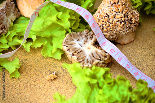 On the table, green lettuce leaves and early steppe marine fungus (Lat.Morchella steppicola) or fungus (Verpa bohemica). Ingredient. Control of excess weight. Vegetarian and diet food. photo