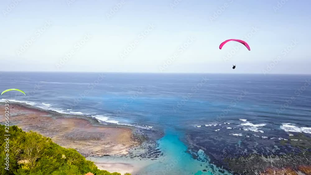 Red hang-glider floats over the ocean Freedom Beautiful view Bali holidays Red hang-glider floats over the ocean Freedom Beautiful view Bali holidays