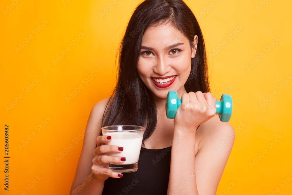 Healthy Asian woman drinking a glass of milk and dumbbell. Healthy Asian woman drinking a glass of milk and dumbbell.